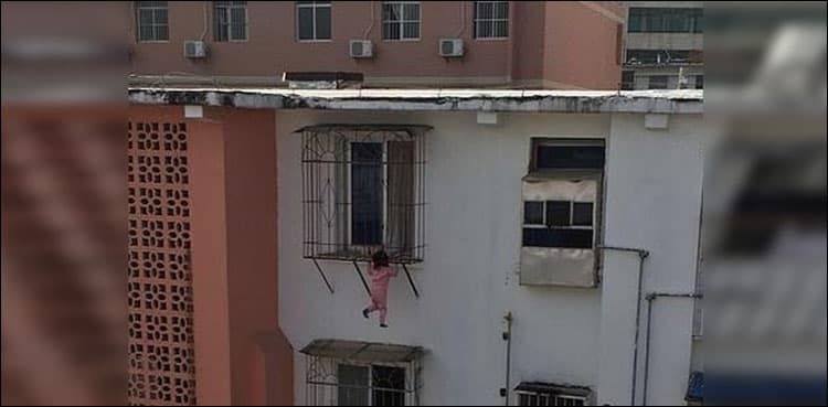 Toddler dangles over five-storey drop after falling out of window