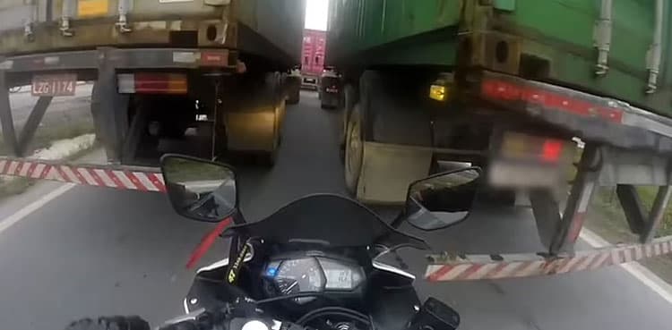 Video: Narrow escape for biker squeezing between heavy trucks